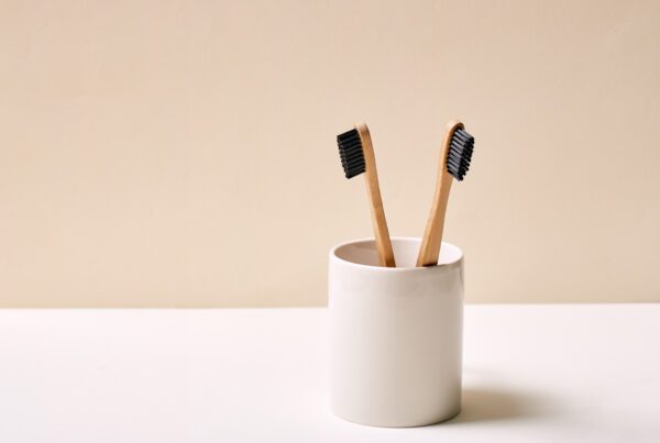 Two bamboo toothbrushes in a white holder
